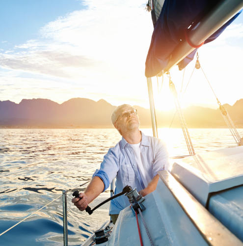 sunrise sailing man on boat in ocean with flare and sunlight on calm morning on the water